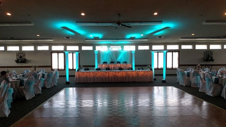 Banquet hall set for a wedding reception with turquoise uplighting